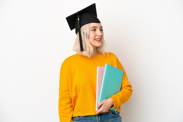 Young university caucasian woman graduate isolated on white background looking side