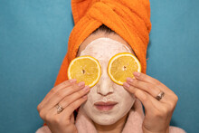 Girl With Lemons On Her Eyes In A Mask, An Orange Towel On A Blue Background