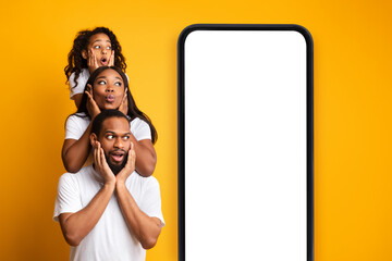 Wall Mural - african american family posing near cellphone with blank screen and looking at device with space for