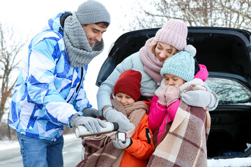 Wall Mural - Young man with his family drinking hot tea on snowy winter day