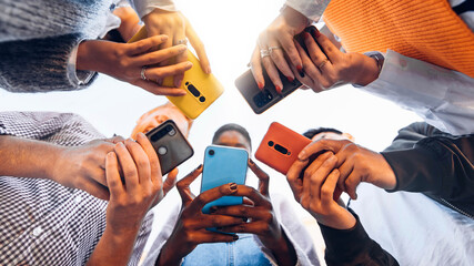 teens in circle holding smart mobile phones - multicultural young people using cellphones outside - 