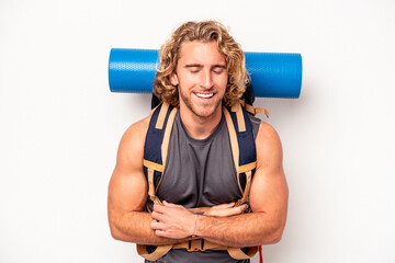 Wall Mural - Young mountaineer caucasian man with a big backpack isolated on white background laughing and having fun.