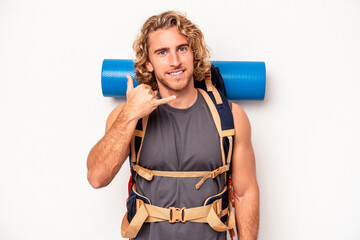 Wall Mural - Young mountaineer caucasian man with a big backpack isolated on white background showing a mobile phone call gesture with fingers.