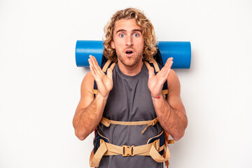 Wall Mural - Young mountaineer caucasian man with a big backpack isolated on white background surprised and shocked.