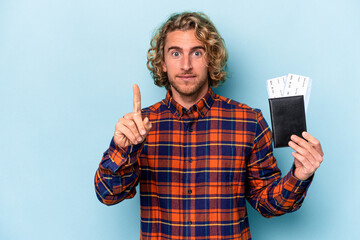 Wall Mural - Young caucasian man holding a passport isolated on blue background showing number one with finger.