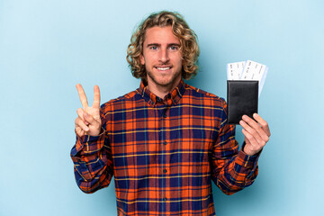 Wall Mural - Young caucasian man holding a passport isolated on blue background showing number two with fingers.