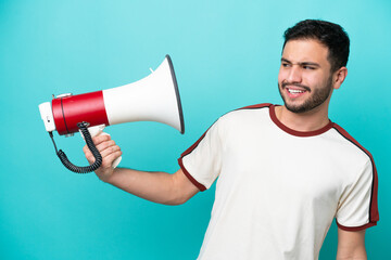 Wall Mural - Young Brazilian man isolated on blue background holding a megaphone with stressed expression