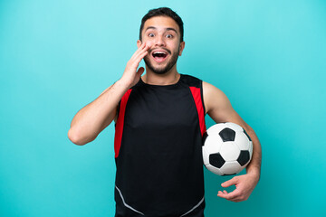 Wall Mural - Young football player Brazilian man isolated on blue background with surprise and shocked facial expression