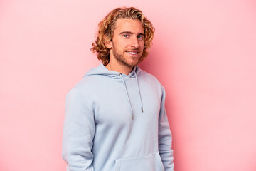 Wall Mural - Young caucasian man isolated on pink background confident keeping hands on hips.