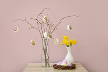 Creative Composition With Tree Branches, Easter Eggs And Narcissus Flowers On Table Near Color Wall
