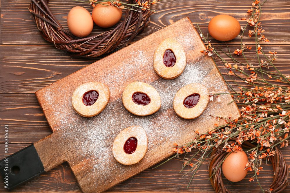 Beautiful Easter composition with tasty cookies, eggs and flowers on wooden background