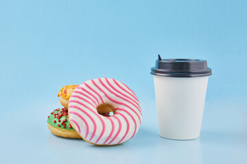 Sweet donut or doughnut with hot cup of fresh brewed coffee or tea. Takeaway paper cup with donuts. Breakfast at the coffee shop concept.