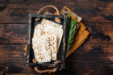 Passover Matzos Of Celebration With Matzo Unleavened Bread In A Wooden Tray With Herbs. Wooden Background. Top View