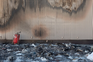 Destroyed building interior due to fire. Black burnt things after arson with red fire extinguisher.