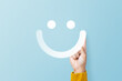 Hand of client show a feedback with smile face sign on blue background. Service rating, feedback, satisfaction concept