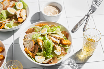 Wall Mural - Caesar salad with chicken in a plate on a light background