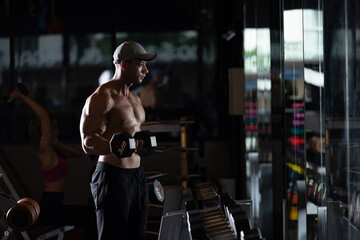 Wall Mural - sports man standing are working out with dumbbells in gym cinematic tone .