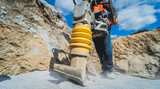 Fototapeta  - Worker uses a portable vibration rammer at construction of a power transmission substation