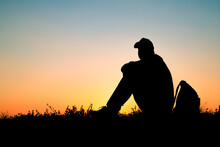 The Silhouette Of Person Sitting On Ground, Rest Of Traveler In Nature