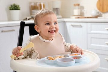 Sticker - Cute little baby eating food in high chair at kitchen