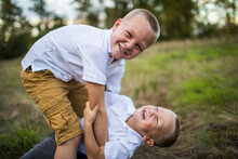 Brothers Playfully Wrestle Outdoors In Grassy Field