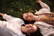 © Cavan Images - Two happy young women smiling while lying on grass