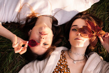 Overhead View Of Two Teenage Girls Lying On Grass During Autumn
