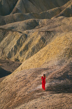 Female Walking In A Red Dress In Death Valley At Zabriskie Point