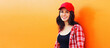 © rohappy - Summer portrait of happy smiling young woman wearing a red baseball cap on colorful orange background