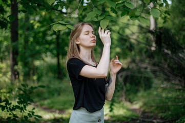 Girl in green forest. Practice of meditation and interaction with nature