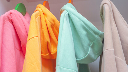 Wall Mural - Close-up Modern multi-colored hoodies on a hanger. Unisex clothes on a hanger.