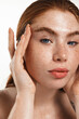 Skin care and beauty. Close up of redhead plus-size, chubby woman with thick eyebrows and glowing clear skin, showing face without acne, standing over white background