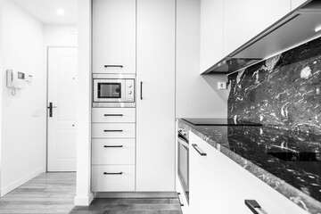 Apartment kitchen with black marble top and wall with long cabinets and drawers