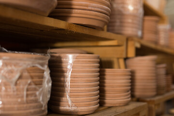 Wall Mural - Closeup of natural clay plates for flower pots wrapped in stretch film on shelves in store ..