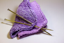 Macro Abstract Texture Background Of Hand-knitted Yarn Wash Cloths In A Simple Garter Stitch, With Knitting Needles, In Varying Shades Of Purple, Pink And White