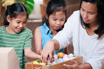 Wall Mural - Asian mother and her daughters are playing with baby bunny and decorating easter eggs preparing for Easter at home. Happy family Happy easter Happy holiday.