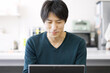 © mapo - パソコンを使って家で仕事をするアジア人男性