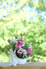 Canvas Print - beautiful Easter composition with decorative easter bunny vase and  flowers bouquet on natural green background. Happy Easter concept