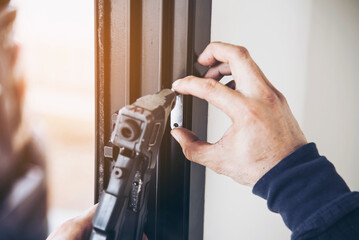 Man doing aluminum frame with glasses and wire screen door and window installation work in construction site