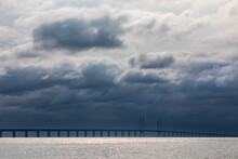 Cloudy Sky Over Sound Strait With Silhouette Of Oresund Bridge In Background