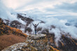 © Westend61 - Female hiker standing with raised arms on top of outcrop in autumn mountains of North Caucasus