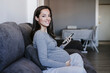 © Westend61 - Smiling pregnant woman with smart phone sitting on sofa at home