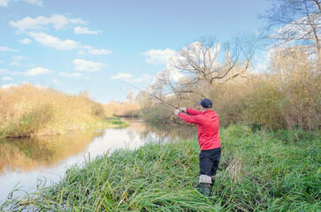 Wall Mural - Angler athlete casts spinning rod into the river.