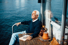 Senior Man Sitting By Table At Houseboat On Sunny Day