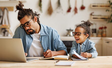 Young African American Dad Working Remotely On Laptop With Child Son At Home