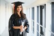 © Serhii - Happy Indian university student in graduation gown and cap holding diploma certificate.