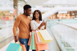 © Prostock-studio - Portrait of excited black spouses using phone holding shopping bags