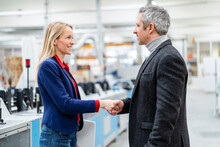 Smiling Blond Businesswoman Shaking Hands With Colleague In Factory