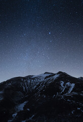Wall Mural - A vertical shot of a slope of a snowy mountain under the starry night sky