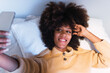 © Westend61 - Young woman taking selfie through mobile phone in bedroom